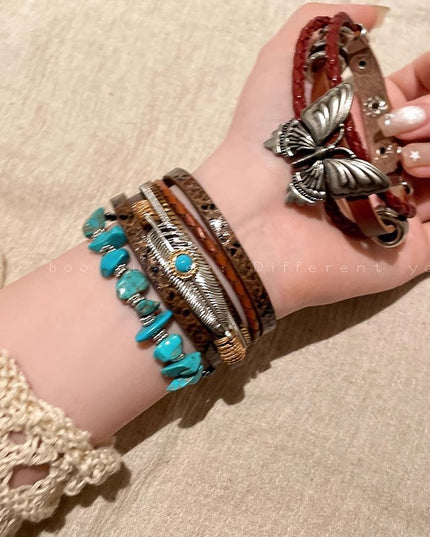 Hand wearing multiple bracelets with a butterfly charm on a beige background