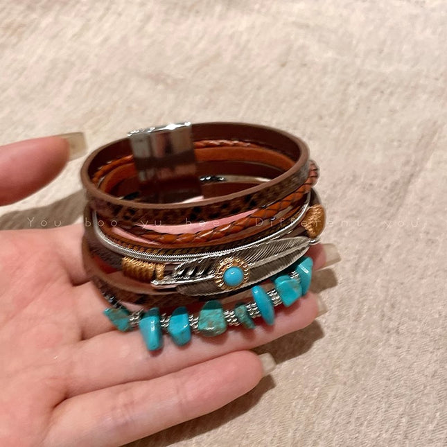 Stack of leather and metal bracelets with turquoise stones on a beige background