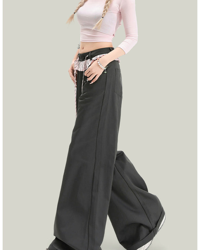 Person wearing a light pink long-sleeve top and black wide-leg pants on a gray background