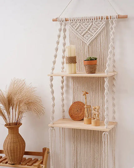 Macrame wall hanging with shelves and decorative items against a white wall