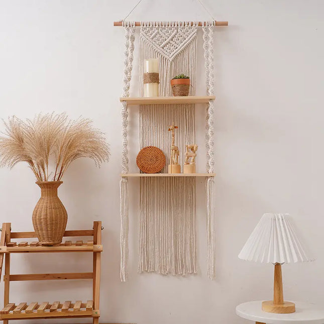 Macrame wall hanging with shelves and decorative items against a white wall.