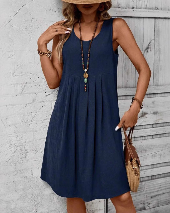 Woman wearing a navy blue dress with a wooden floor and white wall background