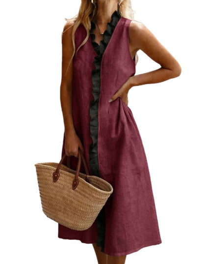 Woman wearing a sleeveless burgundy and black ruffle-trim linen midi dress, holding a woven straw tote bag