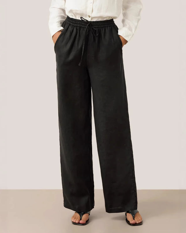 Person wearing black wide-leg pants and a white shirt on a plain background