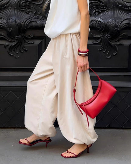 Women holding a red handbag against a black decorative wall.