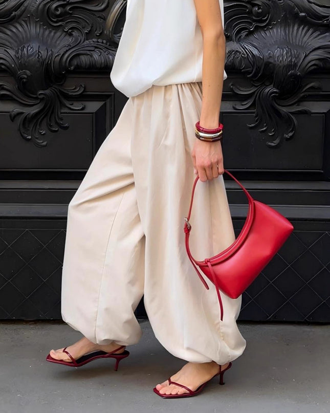 Women holding a red handbag against a black decorative wall.