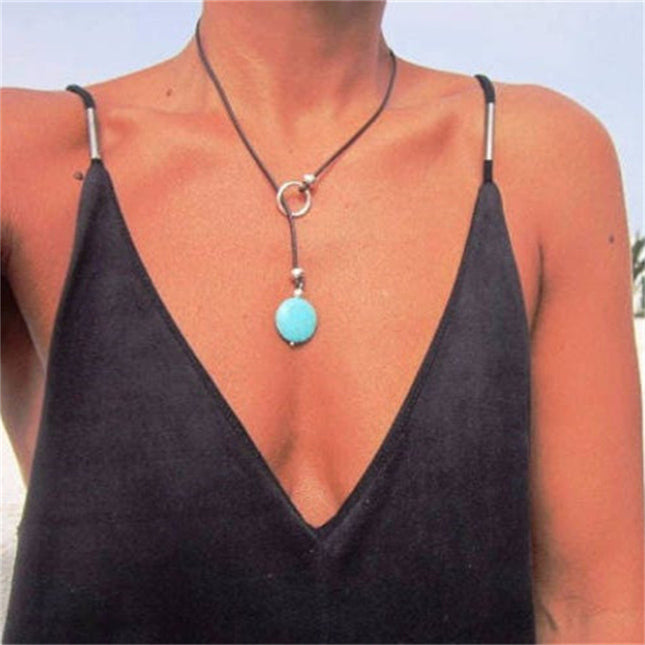 Person wearing a black top with a necklace featuring a turquoise pendant.