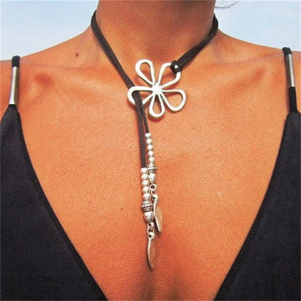 Necklace with a white flower pendant and silver accents on a person wearing a black top.