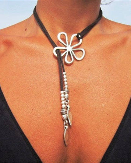 Necklace with a white flower pendant and silver accents on a person wearing a black top.