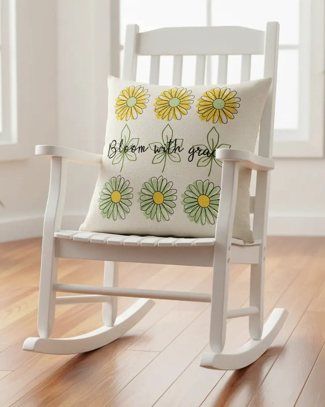 White rocking chair with a decorative pillow featuring floral designs and text on a wooden floor.