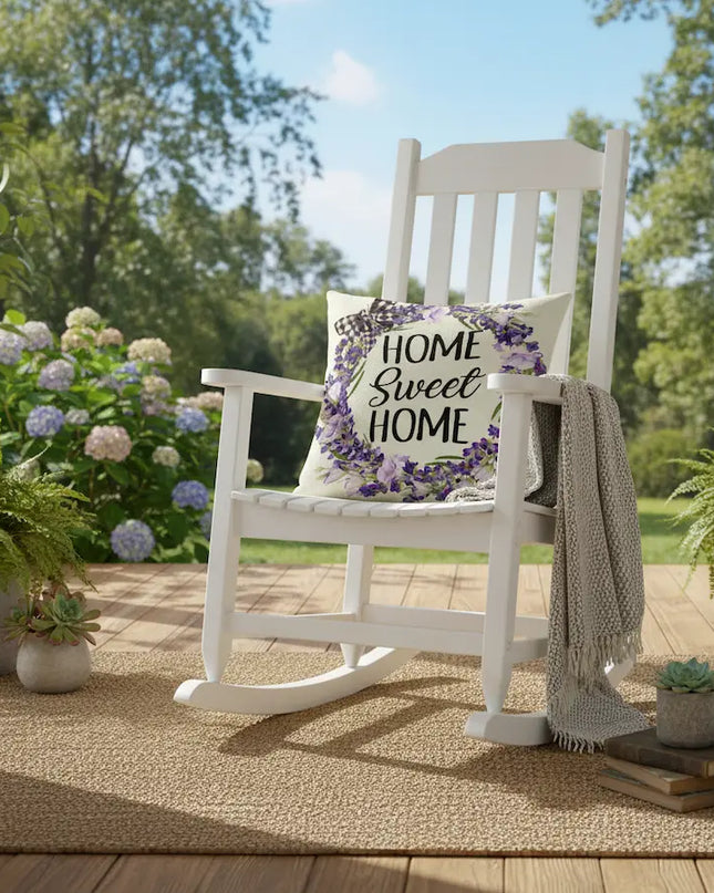 White rocking chair with a 'Home Sweet Home' pillow on a porch with plants and flowers.