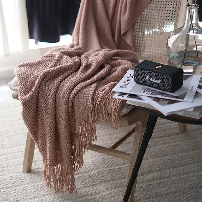 Pink blanket draped over a chair with a Marshall speaker and magazines on a table.