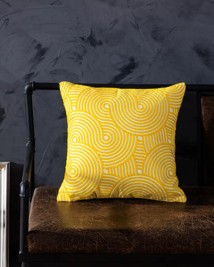 Yellow patterned pillow on a dark brown chair against a dark gray wall.