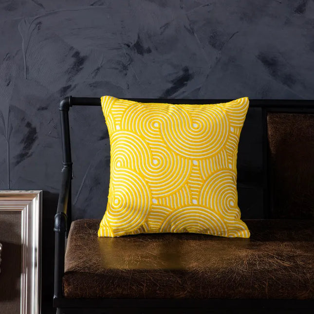 Yellow patterned pillow on a dark brown chair against a dark gray wall.