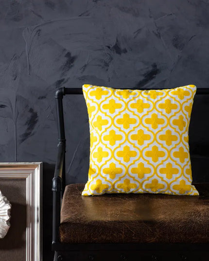Yellow patterned pillow on a dark brown chair against a textured dark gray wall.