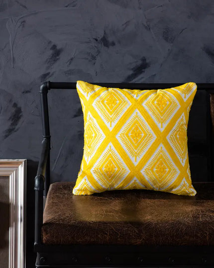 Yellow patterned pillow on a dark brown couch against a dark gray wall.