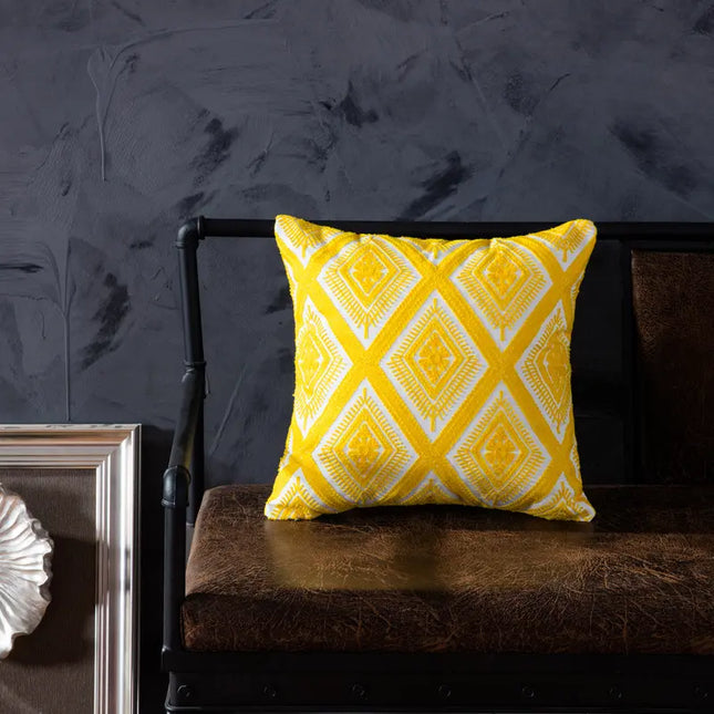 Yellow patterned pillow on a dark brown couch against a dark gray wall.