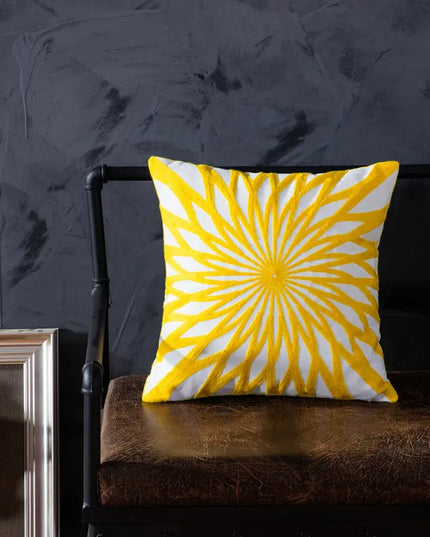 Yellow and white patterned pillow on a brown chair against a dark textured wall.