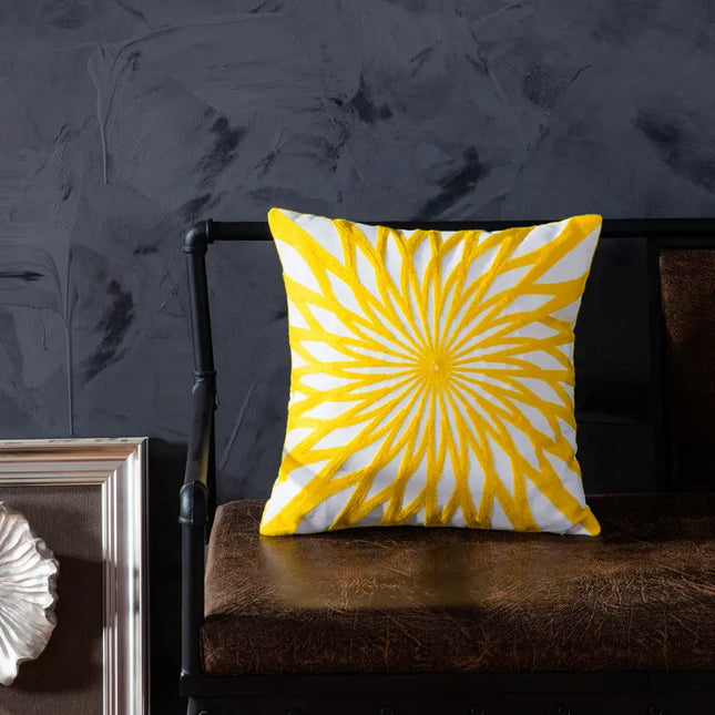Yellow and white patterned pillow on a brown chair against a dark textured wall.