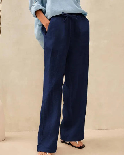 Person wearing navy wide-leg pants and a light blue shirt on a beige background