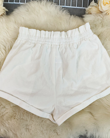 White shorts on a fluffy white surface with flowers around