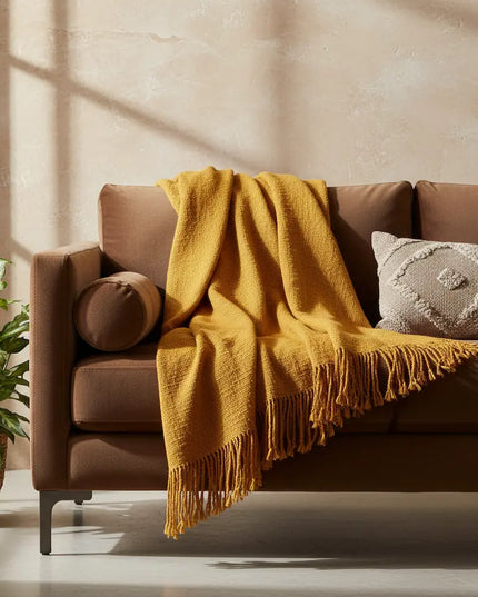 Brown sofa with a yellow blanket and decorative pillows in a cozy living room.