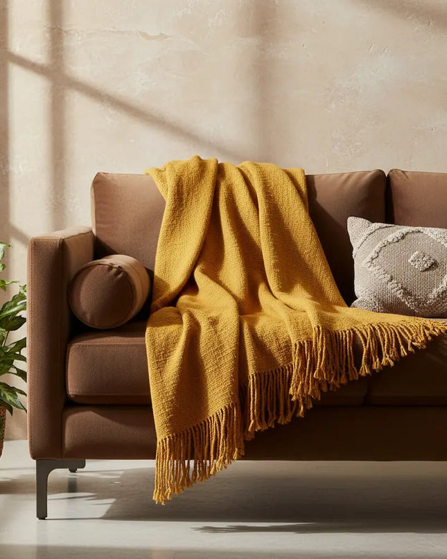 Brown sofa with a yellow blanket and decorative pillows in a cozy living room.
