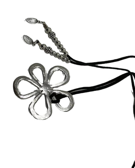 Metal flower-shaped pendant on a black cord against a white background