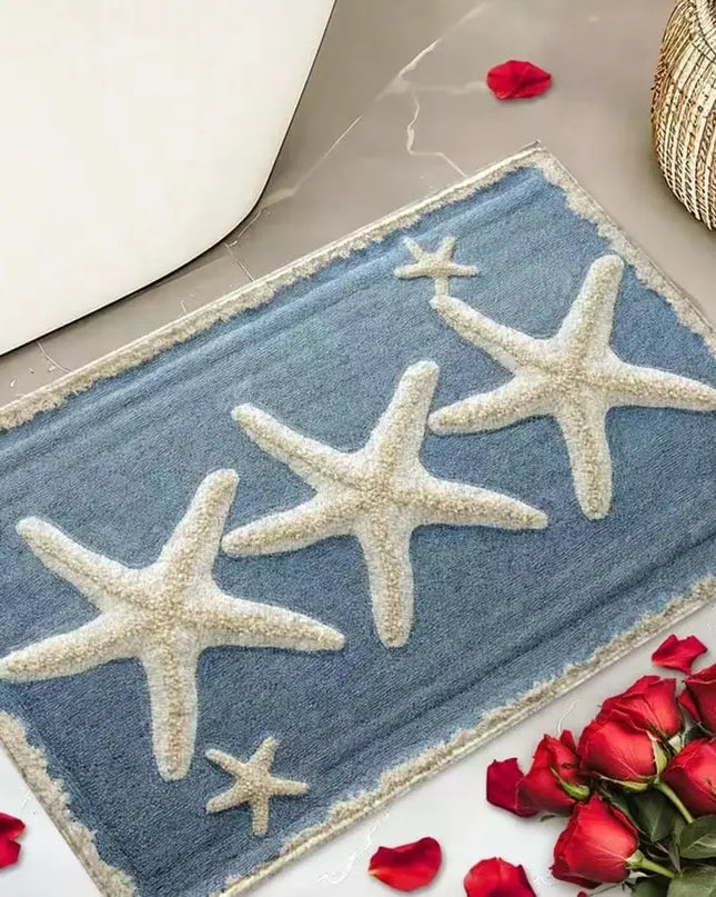 Decorative doormat with starfish design on a floor with red roses and petals.