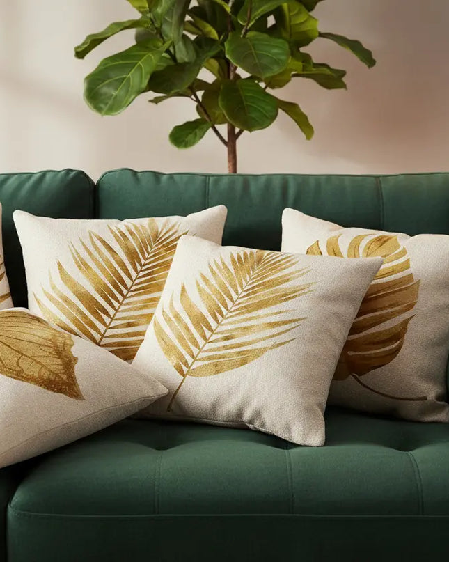 Green sofa with decorative pillows featuring leaf patterns in a living room setting.