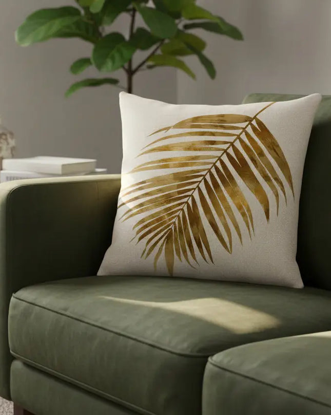 Green sofa with a decorative pillow featuring a leaf pattern in a living room setting.