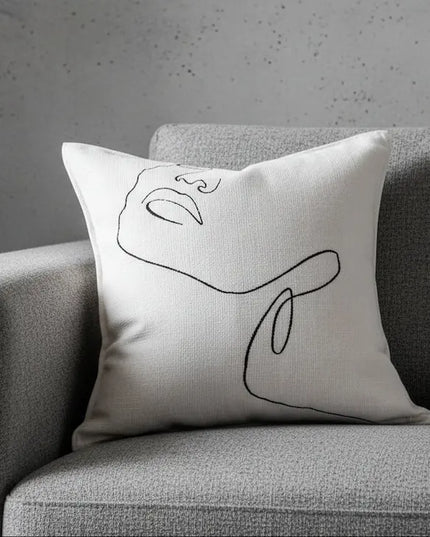 Decorative pillow with abstract design on a gray sofa against a neutral background