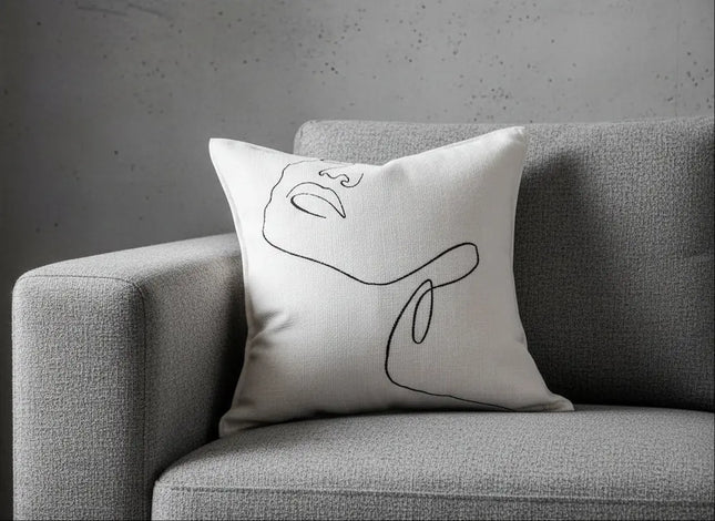 Decorative pillow with abstract design on a gray sofa against a neutral background