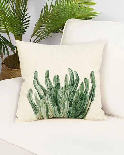 Decorative pillow with cactus design on a white couch with a plant in the background