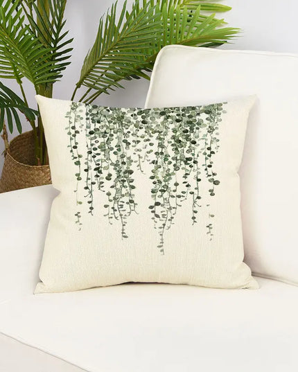 Decorative pillow with plant pattern on a white couch with plants in the background