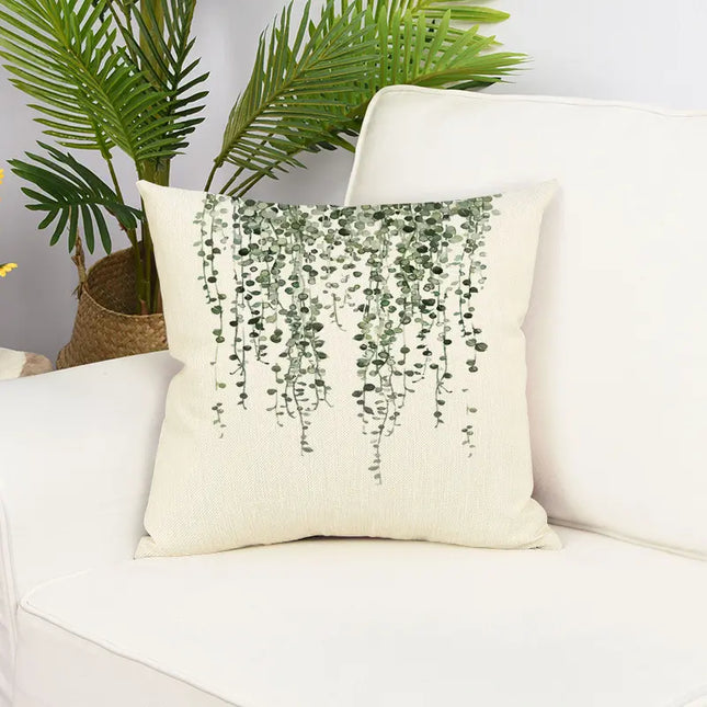 Decorative pillow with plant pattern on a white couch with plants in the background