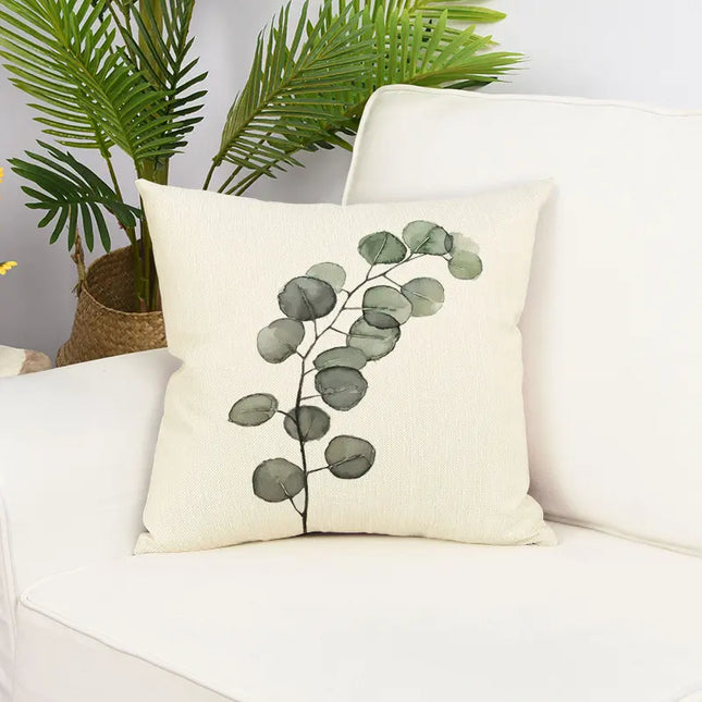 Decorative pillow with eucalyptus design on a white couch with plants in the background