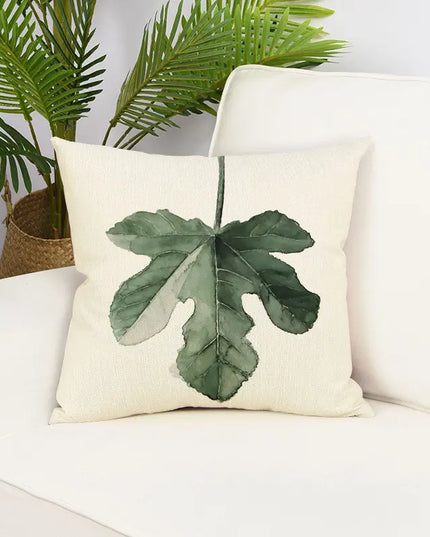 Decorative pillow with leaf design on a white couch with plants in the background