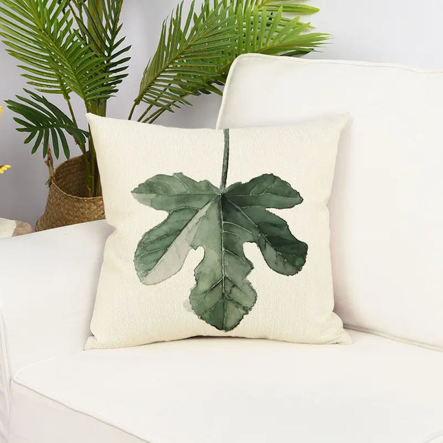 Decorative pillow with leaf design on a white couch with plants in the background