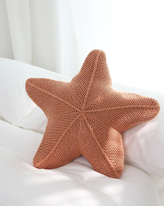 Star-shaped knitted pillow on a white surface