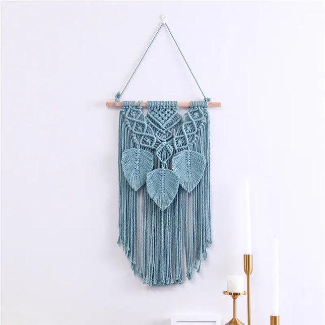 Decorative macrame wall hanging with leaf patterns on a white wall