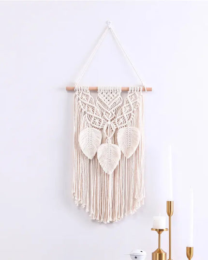 Macrame wall hanging with leaf patterns on a white wall