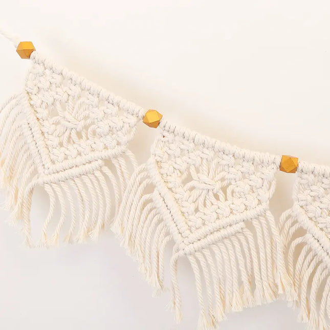 Macrame wall hanging with wooden beads on a white background