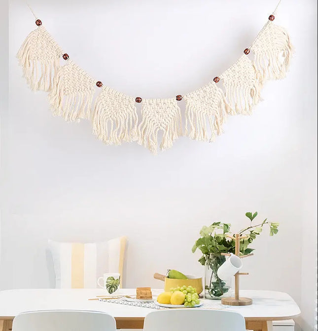 Macrame wall hanging above a dining table with fruit and decor items.