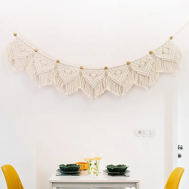 Macrame wall hanging above a dining table with yellow chairs.