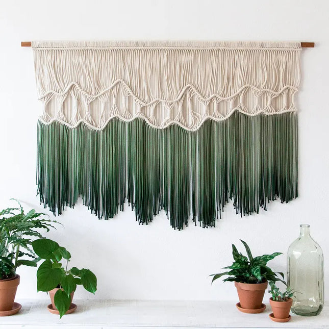 Macrame wall hanging with white top and green bottom on a white background