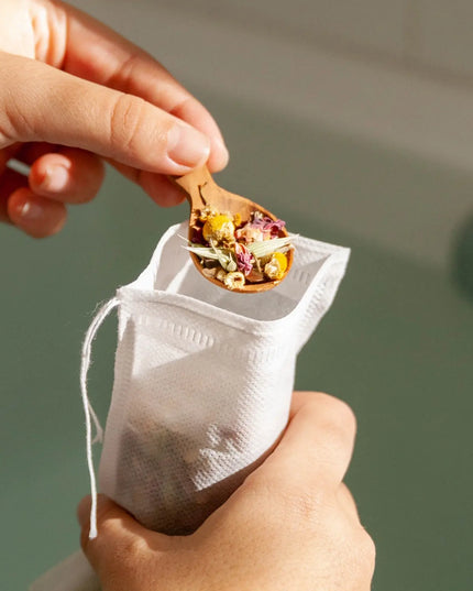 Herbal Bath Tea compostable tea bag with organic herbs on a wooden spoon