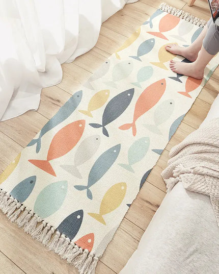 Colorful fish-patterned rug on a wooden floor with a person using a laptop.