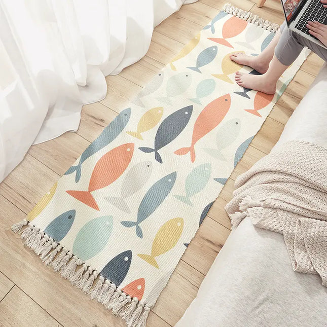 Colorful fish-patterned rug on a wooden floor with a person using a laptop.