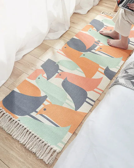 Colorful animal-patterned rug on a wooden floor with a person using a laptop.